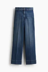 Pantalón de jean de corte wide leg, tiro alto con cierre y doble botón frontal. Presenta perneras amplias con pliegues marcados en la parte delantera y trasera, y dobladillo ancho.