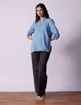 Blusa de lyocell color azul claro, con cuello camisero, escote en V con tapeta de botones y mangas largas con presilla para regular el largo.