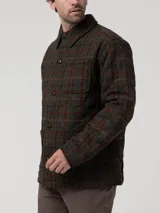 Chaqueta de hombre con estampado de tartán en tonos verde oscuro, marrón, rojo y azul. Presenta cuello camisero, cierre frontal con botones, un bolsillo de parche en el pecho y dos bolsillos laterales.