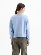 Buzo de corte oversize color marrón chocolate, con cuello redondo y diseño estampado de flores en la parte frontal. Presenta mangas largas con puños ajustados.