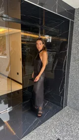 Vestido largo negro con escote halter cruzado y abertura frontal. El ruedo presenta un detalle de flecos.