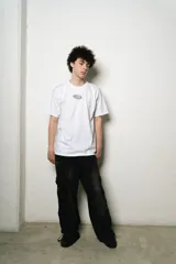 Remera blanca de algodón, corte regular fit, con un pequeño estampado ovalado en el pecho y un gran estampado de firma estilizada en la espalda.