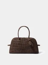 Bolso de mano Jacquemus modelo Le Turismo, confeccionado en cuero con textura de efecto cocodrilo. Presenta un diseño estructurado con asas superiores, cierre de cremallera y un detalle de nudo decorativo en uno de los laterales.