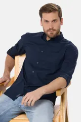 Camisa azul marino de manga larga con cuello camisero, cierre frontal de botones, bolsillo en el pecho y diseño liso.