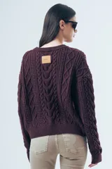 Sweater de punto color bordó con diseño de trenzas y relieves. Presenta cuello redondo, mangas largas y terminaciones acanaladas en puños y ruedo.