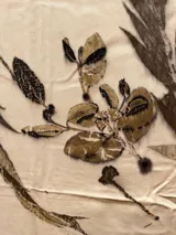 Mantel rectangular de viscosa color crema con estampado de hojas y flores en tonos marrones y dorados.