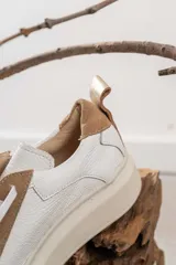 Championes de cuero con diseño de paneles en color blanco y tostado. Presentan suela de plataforma, cordones planos al tono y detalle de tirador en el talón.