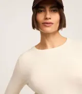 Suéter ajustado de punto color crema, con cuello redondo y mangas largas con botones metálicos en los puños. Confeccionado con viscosa sostenible.
