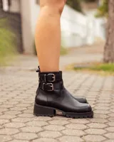 Botas cortas de cuero negro con suela track de goma y dos correas con hebillas metálicas ajustables en el tobillo.