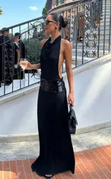 Vestido largo negro con escote halter drapeado, espalda descubierta y una banda de lentejuelas negras en la cintura.
