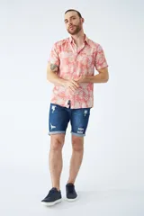 Camisa de manga corta con estampado botánico de hojas en tonos azul y blanco. Presenta cuello clásico, cierre frontal abotonado y corte slim.