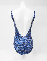 Malla entera estampada en tonos de azul, con escote en V, breteles regulables y un aplique metálico decorativo en el centro del busto. Cuenta con copa armada interna y forro.