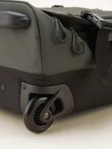 Valija gris con ruedas, manija extensible y múltiples bolsillos con cierre.