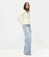 Pantalón wide leg de tiro bajo confeccionado en jean de algodón, con cierre frontal y aplicación de brillos y tachas en los laterales.