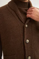 Cardigan marrón tejido con cuello smoking, cierre con botón y bolsillos delanteros.