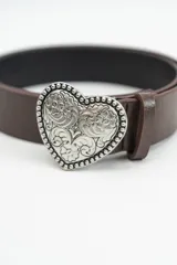 Cinturón negro con hebilla metálica plateada en forma de corazón, con detalle de relieve floral y borde texturizado.