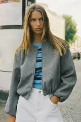 Chaqueta bomber de cuello redondo y manga larga con diseño holgado. Presenta cierre frontal con cremallera, bolsillos delanteros de vivo y acabados elásticos en los puños y el ruedo.