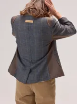 Blazer de denim estructurado con solapas clásicas, cierre frontal de un botón y bolsillos laterales con solapa. Presenta costuras visibles en contraste y un corte sastrero.