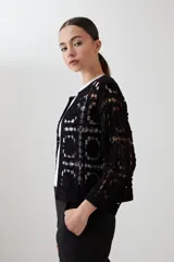 Chaqueta corta de crochet color negro, con diseño de cuadrados calados y manga tres cuartos.