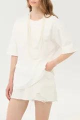 Remera oversize blanca de corte amplio, con cuello redondo y mangas cortas de hombros caídos.