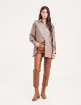 Camisa oversized con terminación metalizada color gris plomo. Tiene botones a tono en el delantero, largo por debajo de la cadera y tajos a los costados.