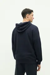 Canguro de felpa azul marino con textura, logo estampado en el pecho y capucha ajustable.