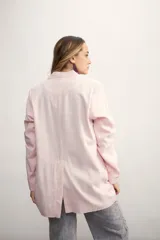 Blazer de mujer color rosa pálido, de corte recto y largo, con solapas de muesca y un solo botón frontal marrón. Presenta bolsillos de parche en la parte delantera y mangas tres cuartos.
