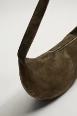 Bolso de hombro con diseño de media luna, confeccionado en piel con acabado de serraje. Cuenta con un asa integrada y cierre principal mediante cremallera.
