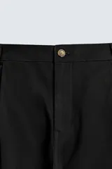 Pantalón chino de corte wide fit confeccionado en tejido de algodón. Presenta pliegues frontales, bolsillos laterales y bolsillos traseros de vivo, con cierre frontal de cremallera y botón.