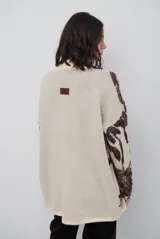 Buzo de tejido de punto con diseño floral en contraste, cuello redondo y mangas largas. Presenta una textura suave y un corte holgado.