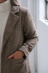 Blazer de corte recto con estampado de cuadros tipo príncipe de gales en tonos marrones y beige. Presenta solapas clásicas, bolsillos frontales aplicados y mangas largas.