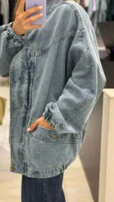 Campera de jean con diseño de monograma grabado, cuello alto, cierre frontal y puños elásticos. Presenta bolsillos frontales con solapa y botones metálicos.