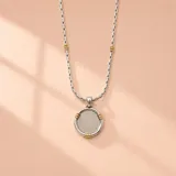 Collar de plata y oro con cadena de eslabones y detalles dorados, y un dije colgante redondo con centro texturizado y detalles en oro.