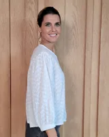 Camisa de manga larga con diseño de rayas verticales y bordados sutiles. Presenta cuello redondo, cierre frontal con botones y mangas abullonadas con volados en los hombros.