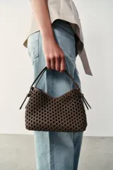 Mini bolso de mano de color marrón con diseño trenzado y doble asa de mano. Incluye función bandolera con correa extraíble, forro interior y cierre mediante botón imantado.