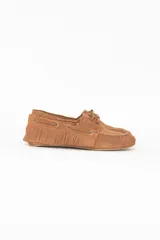 Mocasín femenino de gamuza color camel oscuro, con diseño de inspiración náutica, flecos decorativos alrededor del talón, cordones laterales y costuras visibles.