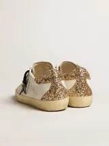 Zapatillas Golden Goose modelo Super-Star en color blanco, con acabado desgastado, la emblemática estrella lateral y detalle en el talón con brillo dorado, además de cordones estampados.