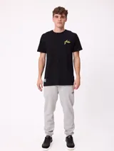 Remera negra de manga corta con gran estampado en la espalda de un paisaje natural montañoso, árboles, carpa y tipografía multicolor.