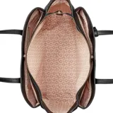 Cartera tipo shopper Guess modelo Griffin, color negro con textura granulada. Cuenta con cierre superior, asas dobles de hombro y placa triangular metálica con logo en el frente. Incluye un colgante decorativo con charms de flores y etiqueta de cuero sintético.
