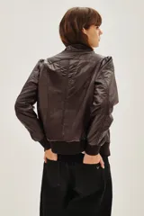 Campera estilo biker color ciruela, con múltiples cierres metálicos decorativos en el frente y mangas. Tiene cuello alto con broches, puños y cintura elastizados.