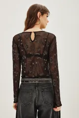 Camisa de mesh transparente con mangas largas y cuello redondo, decorada con bordados de cuentas y lentejuelas en diseño floral.