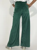 Pantalón de terciopelo gris, de corte palazzo, con bolsillos laterales y cierre frontal con botón y cremallera.