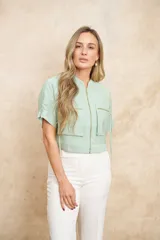 Chaqueta bomber color verde agua, con cierre frontal dorado, bolsillos grandes con cierre y mangas cortas con ajuste mediante lazos.