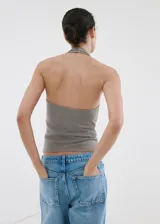 Top gris de corte entallado y escote halter, sin mangas, confeccionado en mezcla de lino y algodón. Presenta un diseño adornado con botones decorativos de nácar a lo largo del escote y los tirantes.