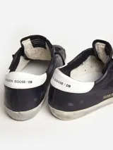 Zapatillas urbanas Golden Goose modelo Super-Star, color negro con estrella blanca en el lateral, detalle trasero en cuero blanco y suela con efecto desgastado.