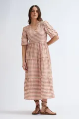 Vestido midi con estampado a cuadros color terracota y crudo, escote en V y mangas abullonadas cortas. Tiene corte imperio y falda escalonada.