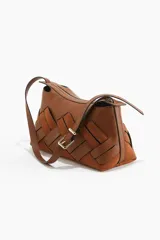 Cartera de hombro color marrón, con diseño trenzado oversized que combina secciones de cuero liso y gamuza. Cuenta con cierre superior, forro interior y correa ajustable con hebilla metálica.