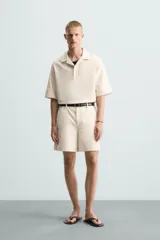 Bermuda de algodón color blanco, de corte relajado, con cintura elástica, bolsillos frontales y bolsillos traseros de plastrón. Cierre frontal con cremallera y botón.