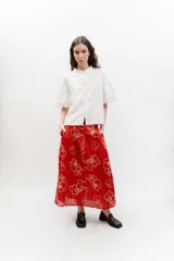 Falda midi de popelina 100% algodón, color rojo con diseño cuadriculado y estampado de flores blancas en líneas de contorno. Cuenta con bolsillos laterales y calce cómodo.