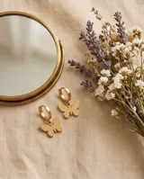 Par de caravanas tipo argolla en acero dorado, con un dije colgante en forma de mariposa minimalista.